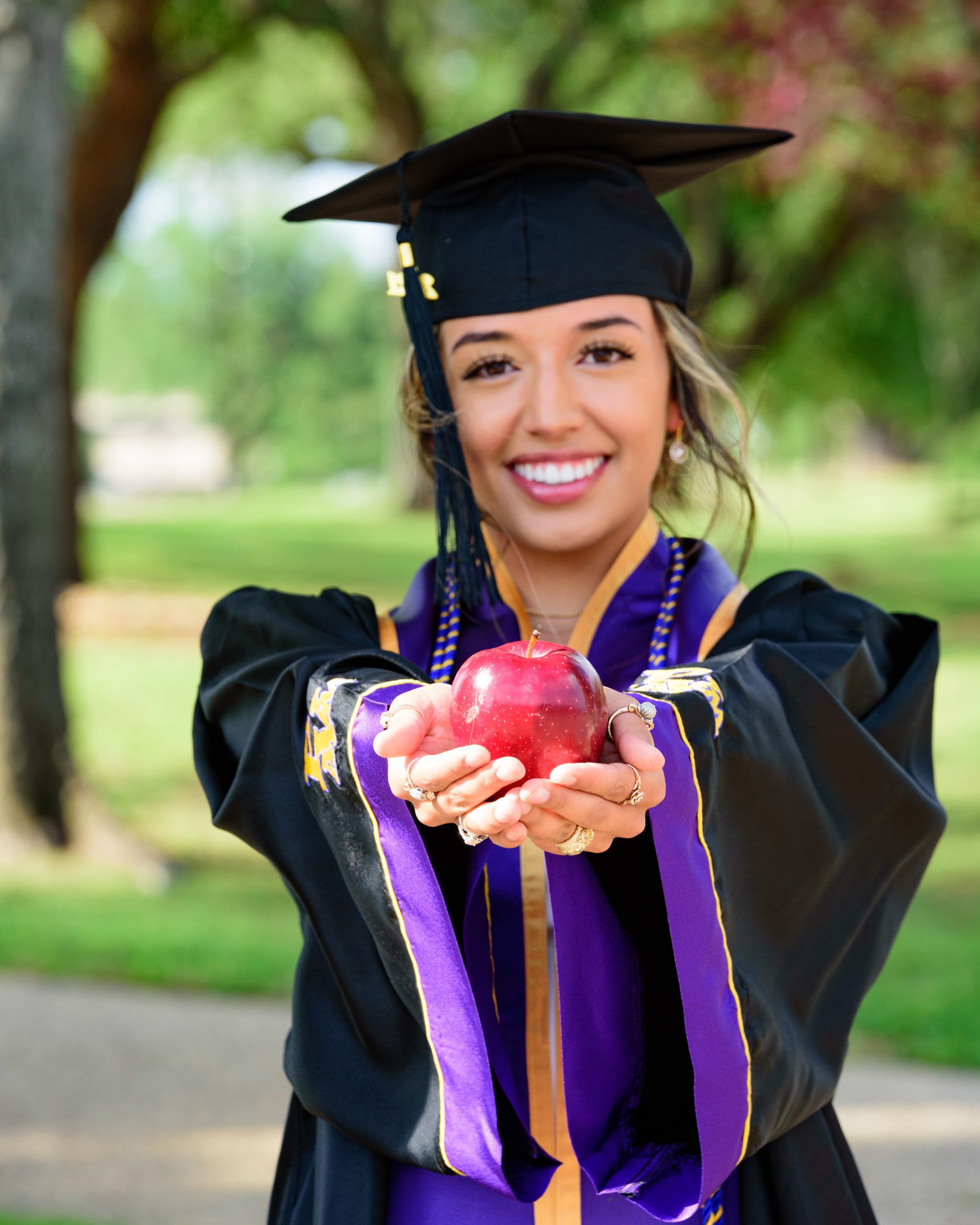 PVAMU graduation photos of college student holding an apple